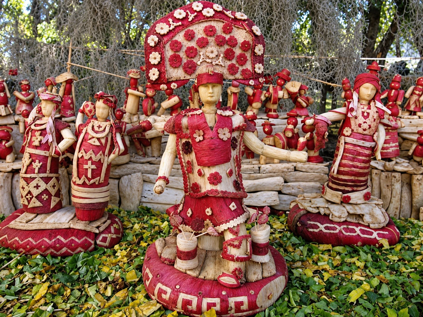 Red-and-white folk figures with elaborate costumes, headpieces and small floral decorations